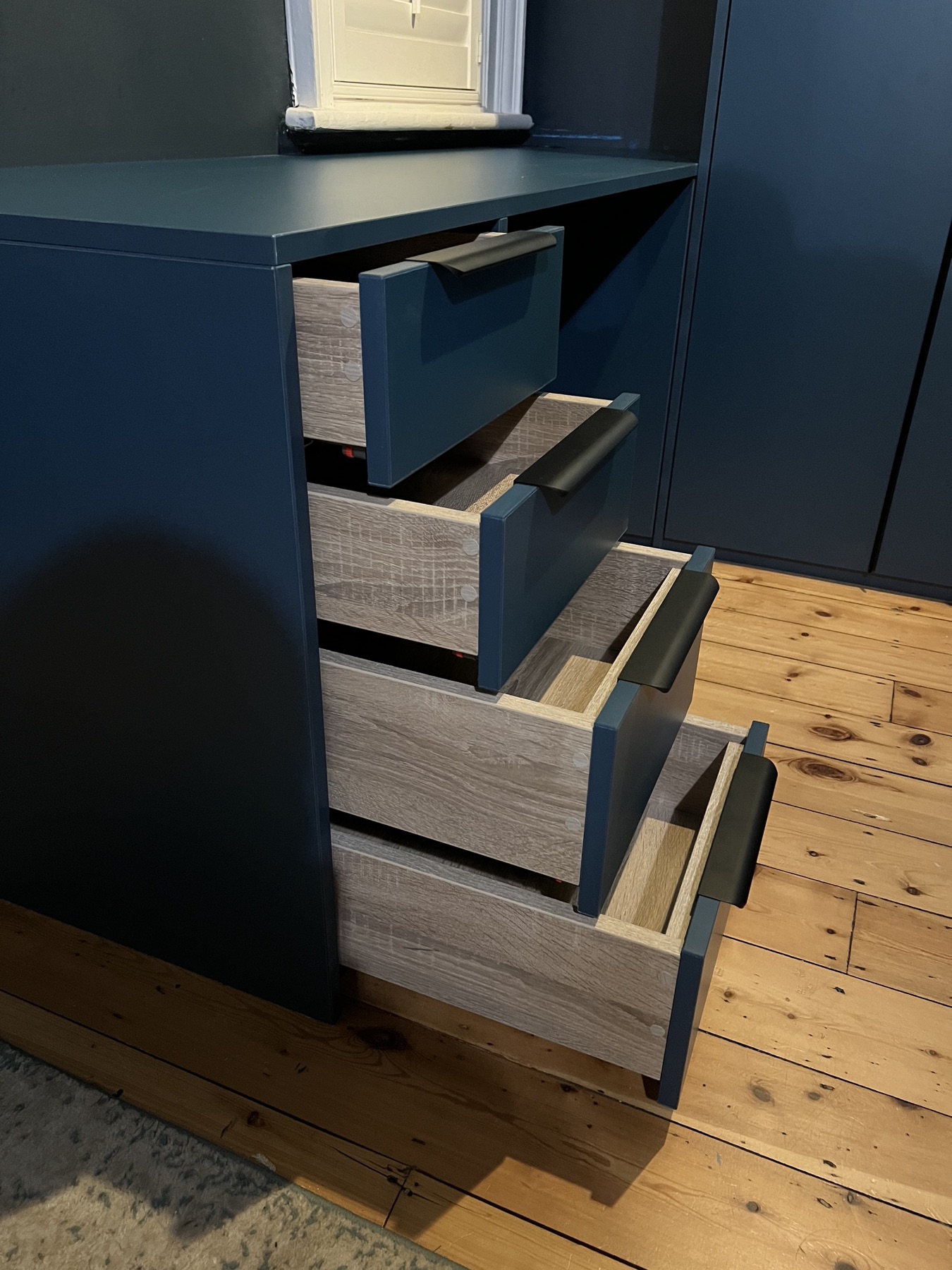 Open drawers within a deep blue fitted dressing area